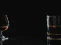 Kieliszek z brandy i szklanka z whisky na ciemnym tle.