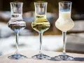 Trzy kieliszki z różnymi alkoholami, w tym grappa. Jak pić grappę? Powoli, delektując się smakiem.