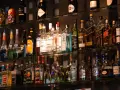 Różne rodzaje martini, szampanów i innych alkoholi na półkach baru.