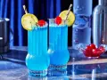 Dwa błękitne drinki Kamikaze, ozdobione cytryną i wiśnią, idealne do picia w letni wieczór.