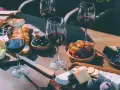 Degustacja merlot: jakie to wino? Kieliszki czerwonego wina, sery, winogrona, oliwki i pieczywo tworzą idealną kompozycję.