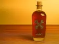 Butelka Bumbu rum z korkiem na drewnianym blacie. Jak pić ten rum? Ciesz się nim powoli, delektując się smakiem.