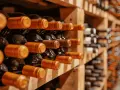 Rzędy butelek wina w drewnianych regałach. Zastanawiasz się, czy wino może się zepsuć? Odpowiedź zależy od wielu czynników, ale odpowiednie przechowywanie jest kluczowe.