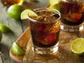 Orzeźwiający drink: bacardi z czymś ciemnym i lodem, ozdobiony plasterkami limonki.