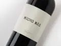 Ciemna butelka wina Mucho Mas, z etykietą z napisem "Mucho Más" i złotym podpisem "Felix Solis".
