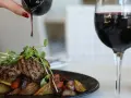 Idealne wino do jagnięciny: soczyste medaliony z ziołami, pieczone warzywa i kieliszek czerwonego wina.