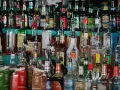 Różnorodne butelki alkoholi, w tym whisky, stoją na półce. Wskazówki, jak przechowywać whisky, mogą być przydatne przy tak bogatym asortymencie.