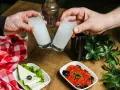 Dwie szklanki z rakı, tradycyjnym tureckim alkoholem, unoszą się do toastu. Obok ser, sałata, sos pomidorowy z bakłażanem i butelka rakı. Idealne połączenie na wieczór.