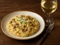 Kremowe risotto z grzybami i kieliszek białego wina. Idealne połączenie, jeśli zastanawiasz się, jakie wino do risotto.