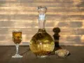 Wódka z pieprzem przepis: nalewka w karafce i kieliszku, obok miseczka z ziarnami pieprzu.