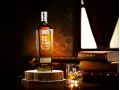 Butelka Kavalan Single Malt Whisky, uznawana za najlepszą polską whisky, obok szklanki z lodem i sterty książek.
