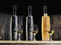 Trzy butelki Octomore, znanej z tego, że jest najbardziej dymna whisky, stoją obok kieliszków z bursztynowym płynem.