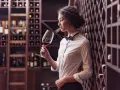 Elegancka sommelierka w piwnicy z winami ocenia aromat czerwonego wina.