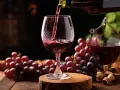 Czerwone wino nalewane do kieliszka, obok kiście winogron. Idealne na domowy przepis na wino z winogron 10l.