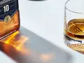 Butelka Ballantine's 10 Years Old i szklanka z bursztynowym płynem, przypominającym smak bourbona.
