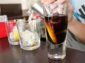 Elegancka porcja whisky z lodem i skórką pomarańczy, przygotowywana w szklance.