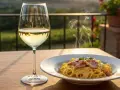 Pyszne spaghetti carbonara paruje, a obok kieliszek złocistego wina półwytrawnego. Idealny wieczór na tarasie.
