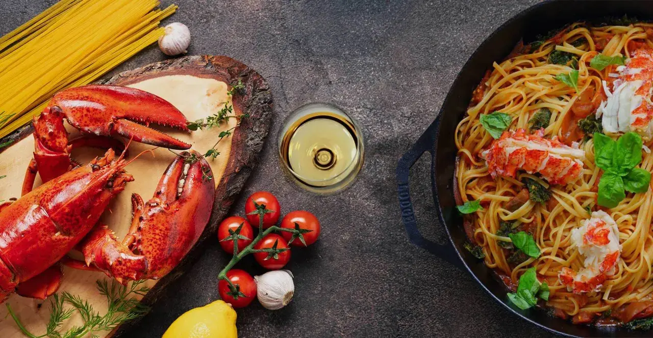 Pyszne spaghetti z homarem, świeże pomidory, czosnek i kieliszek chardonnay wino. Idealna kolacja.