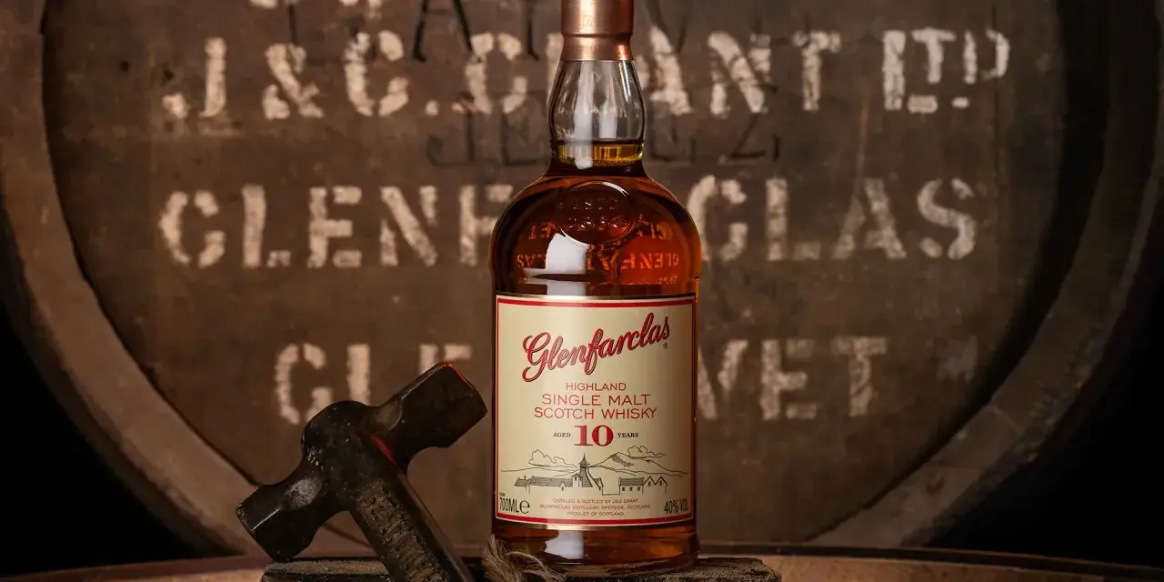 Glenfarclas 10YO, idealny wybór do rankingu top 10 whisky. Butelka na tle beczki z destylarni.