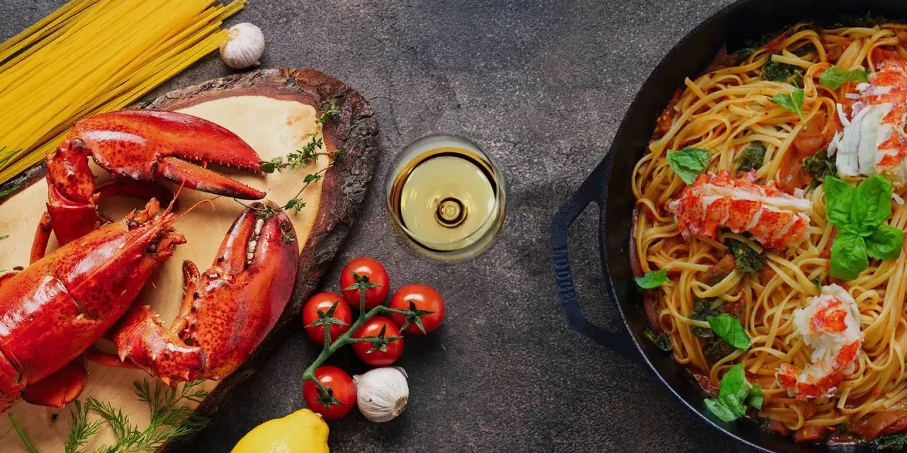 Pyszne spaghetti z homarem, świeże pomidory, czosnek i kieliszek chardonnay wino. Idealna kolacja.
