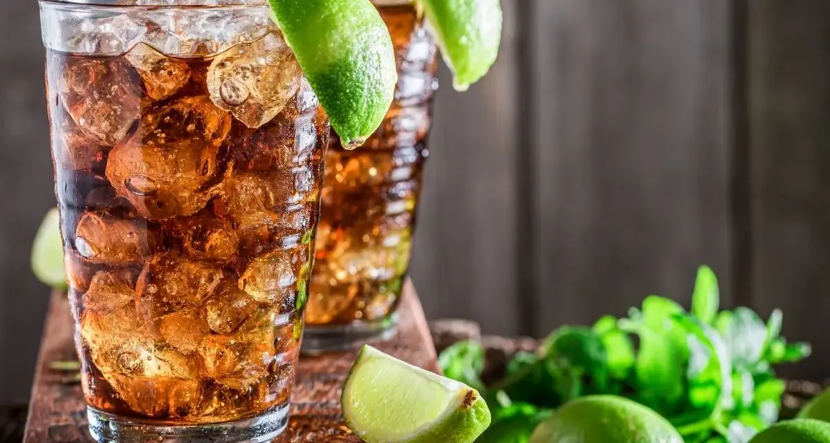 Dwa orzeźwiające drinki z rumem i lodem, ozdobione limonką. Idealne na upalne dni, zastanawiasz się, jaki rum do herbaty będzie najlepszy?