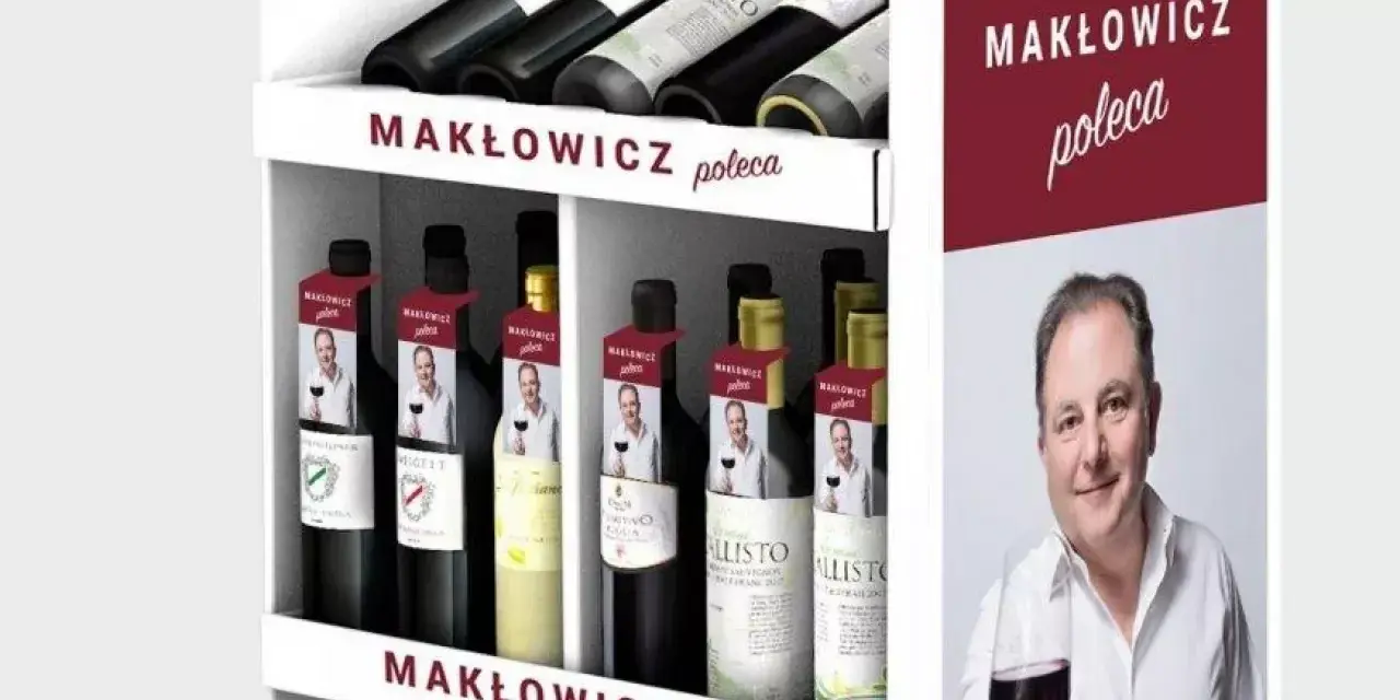 Regał z butelkami wina, z etykietami "Makłowicz poleca" i zdjęciem Roberta Makłowicza.