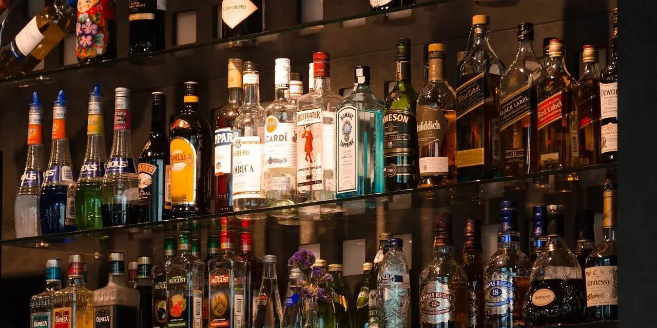 Różne rodzaje martini, szampanów i innych alkoholi na półkach baru.