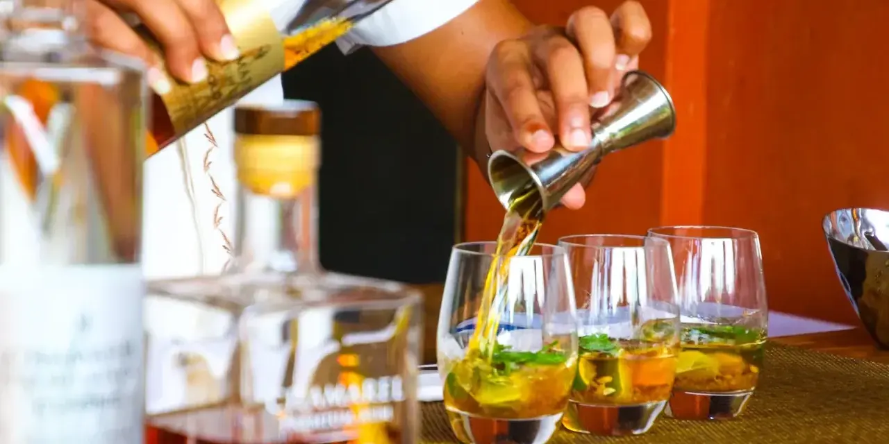 Barman nalewa cachacę do szklanek z lodem i miętą. To popularny brazylijski alkohol.