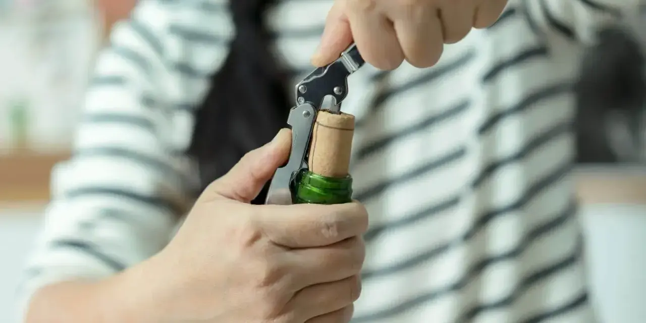 Ręce otwierają butelkę prosecco korkociągiem. Prosty sposób, jak otworzyć prosecco, by zacząć świętowanie.