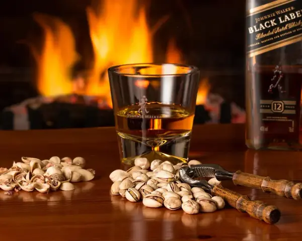 Przy kominku, kieliszek Johnnie Walker i pistacje. Idealny wieczór, czy whisky się chłodzi?