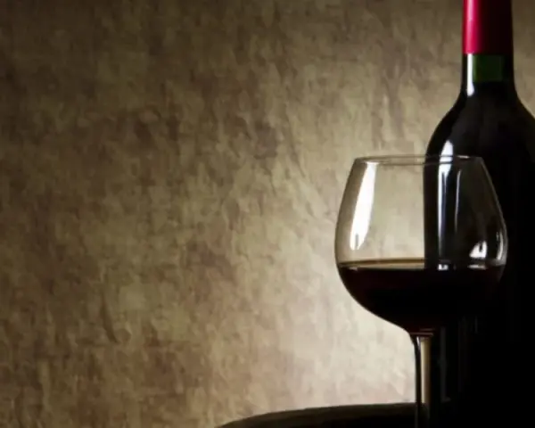Kieliszek z czerwonym winem i butelka na tle. Czy czerwone wino się chłodzi?