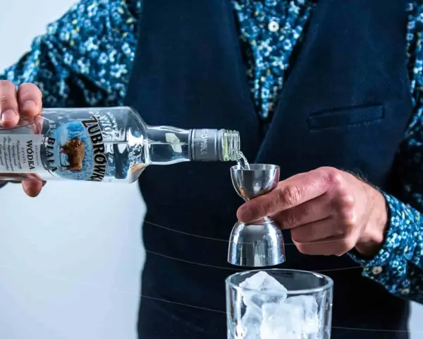 Barman nalewa Żubrówkę do kieliszka z lodem. To może być początek przygotowania drinka z jednej z top 10 wódek w Polsce.