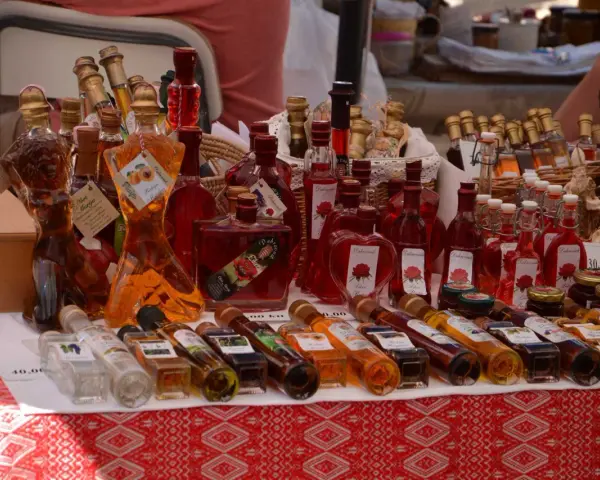 Różnorodne butelki z rakiją, w tym te o fantazyjnych kształtach, prezentują bogactwo smaków. Co to rakija? To tradycyjny alkohol, często owocowy.