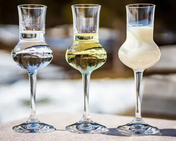 Trzy kieliszki z różnymi alkoholami, w tym grappa. Jak pić grappę? Powoli, delektując się smakiem.