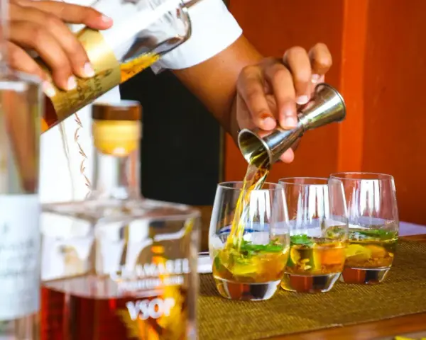 Barman nalewa cachacę do szklanek z lodem i miętą. To popularny brazylijski alkohol.