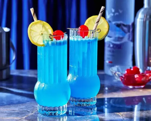 Dwa błękitne drinki Kamikaze, ozdobione cytryną i wiśnią, idealne do picia w letni wieczór.