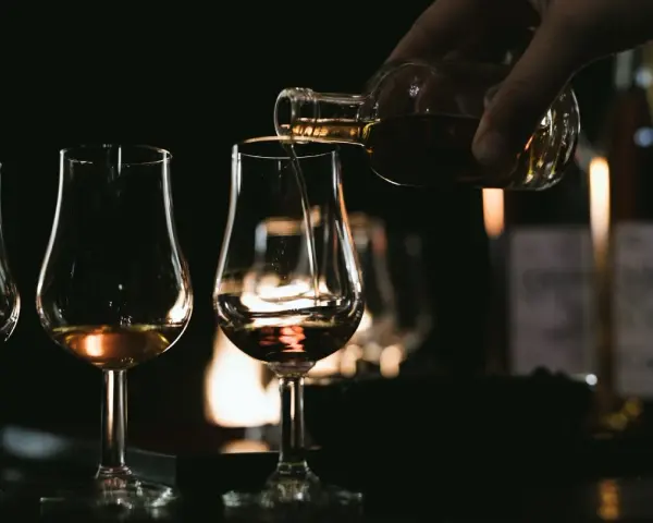 Degustacja koniaku: nalewanie bursztynowego trunku do kieliszków. Poznaj tajniki, jak pić koniak, by docenić jego głębię.