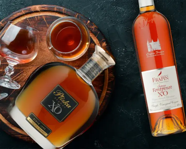 Brandy vs Cognac: butelka Pliska XO Brandy i Frapin Fontpinot XO Cognac, dwa kieliszki z bursztynowym trunkiem.