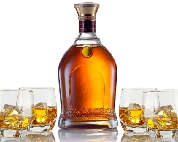 Elegancka butelka whisky i cztery szklanki z lodem. Czy to single malt czy blended, każdy znajdzie coś dla siebie.
