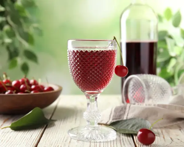 Szklanka z czerwonym winem, wiśnie i butelka. Idealny przepis na wino czerwone z wiśni.
