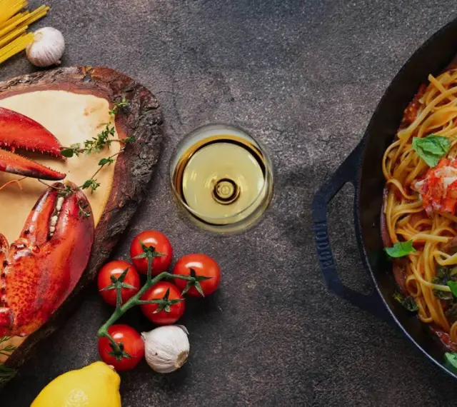 Pyszne spaghetti z homarem, świeże pomidory, czosnek i kieliszek chardonnay wino. Idealna kolacja.