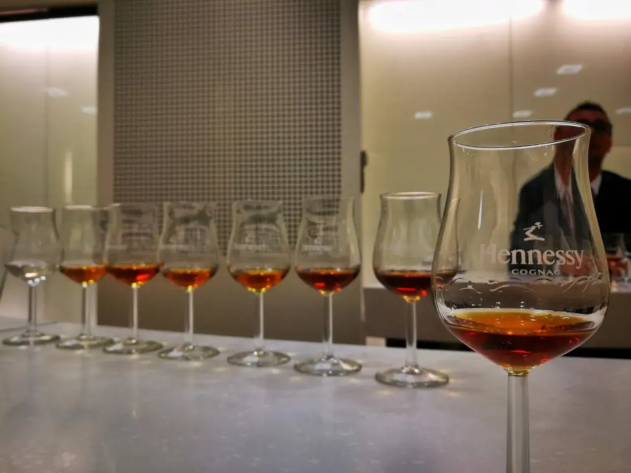 Degustacja Hennessy. Kilka kieliszków z bursztynowym trunkiem, każdy z nich pokazuje inny odcień i sposób, jak pić brandy.