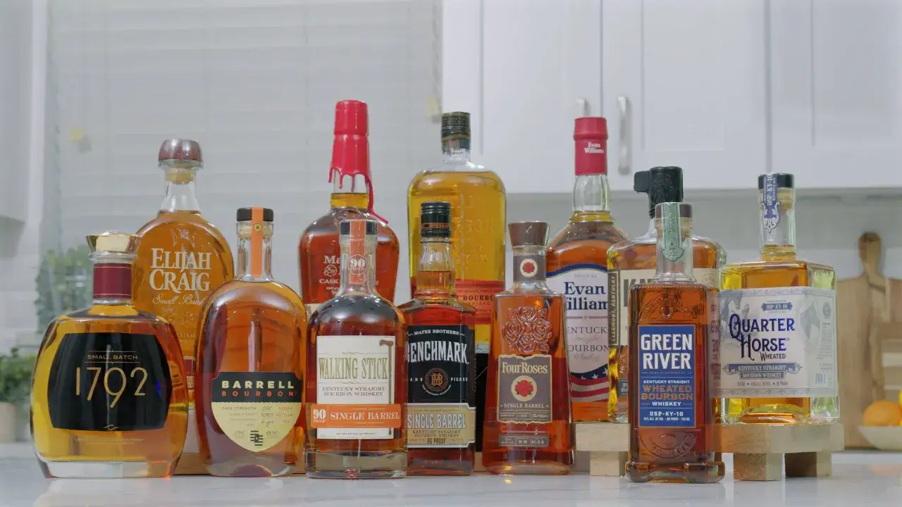 Kolekcja butelek whiskey, w tym kilka bourbonów, stoi na blacie.
