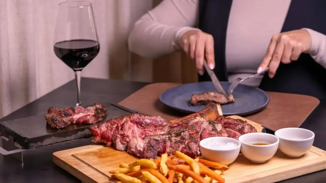 Idealne jakie wino do wieprzowiny? Czerwone wino i soczysta wieprzowina na desce, z frytkami i sosami.