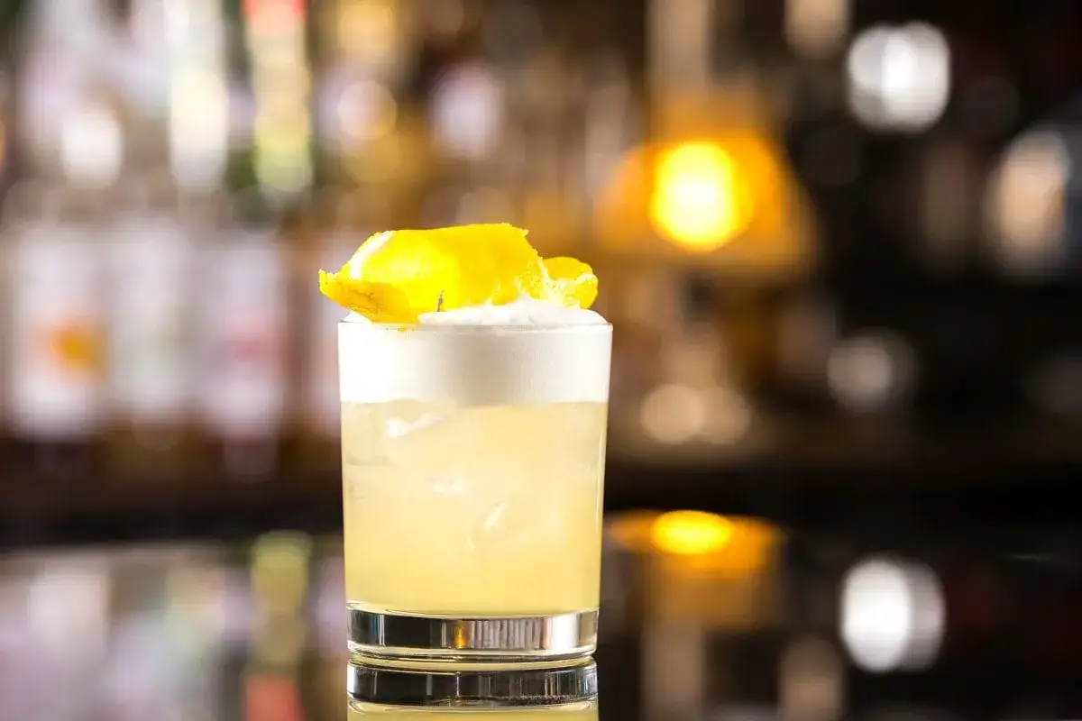 Klasyczny whisky sour z pianką i skórką cytrynową, idealny na wieczór.