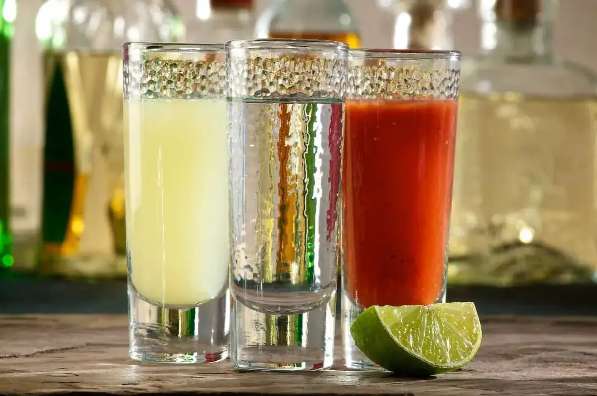 Trzy shoty: jeden z żółtym płynem, drugi z przezroczystym, trzeci z czerwonym, obok limonka. Idealnie, jak się pije tequila!