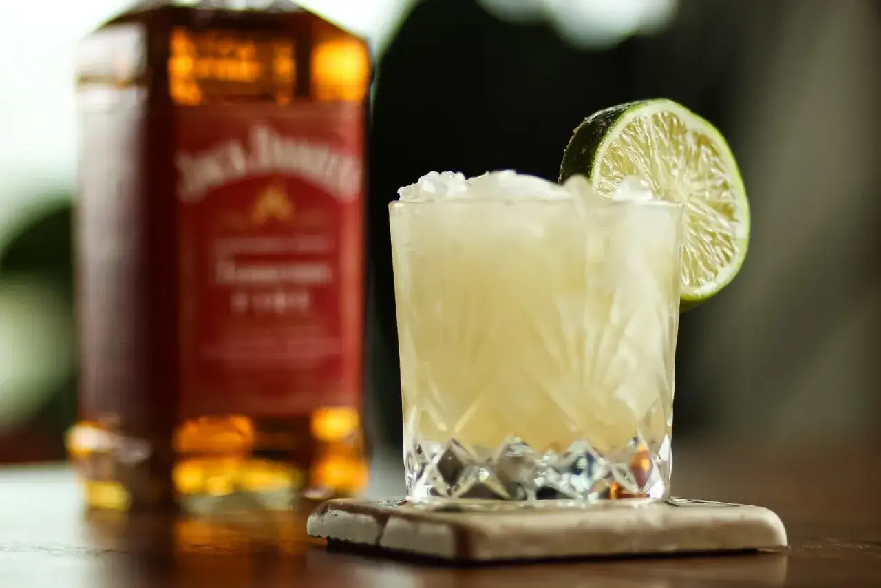Butelka Jack Daniel's i drink z lodem i limonką. Idealny sposób, jak pić Jacka Danielsa, by poczuć jego smak.