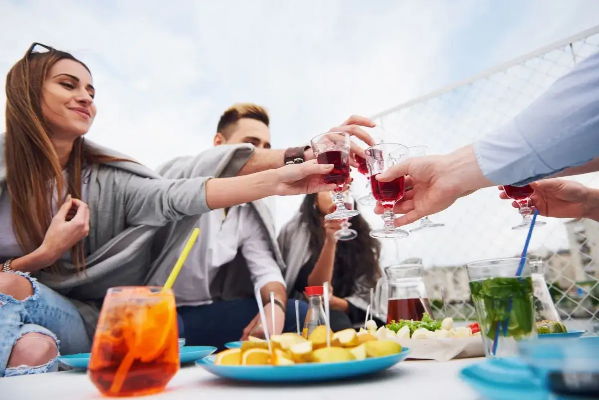 Przyjaciele wznoszą toast czerwonymi drinkami. Czy to już czas na digestif co to?