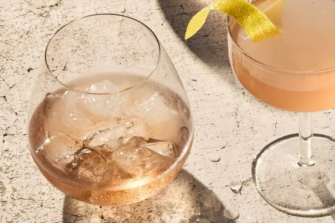 Orzeźwiające wino z lodem w szklance, obok drink z cytrynową skórką. Idealne na upalny dzień.