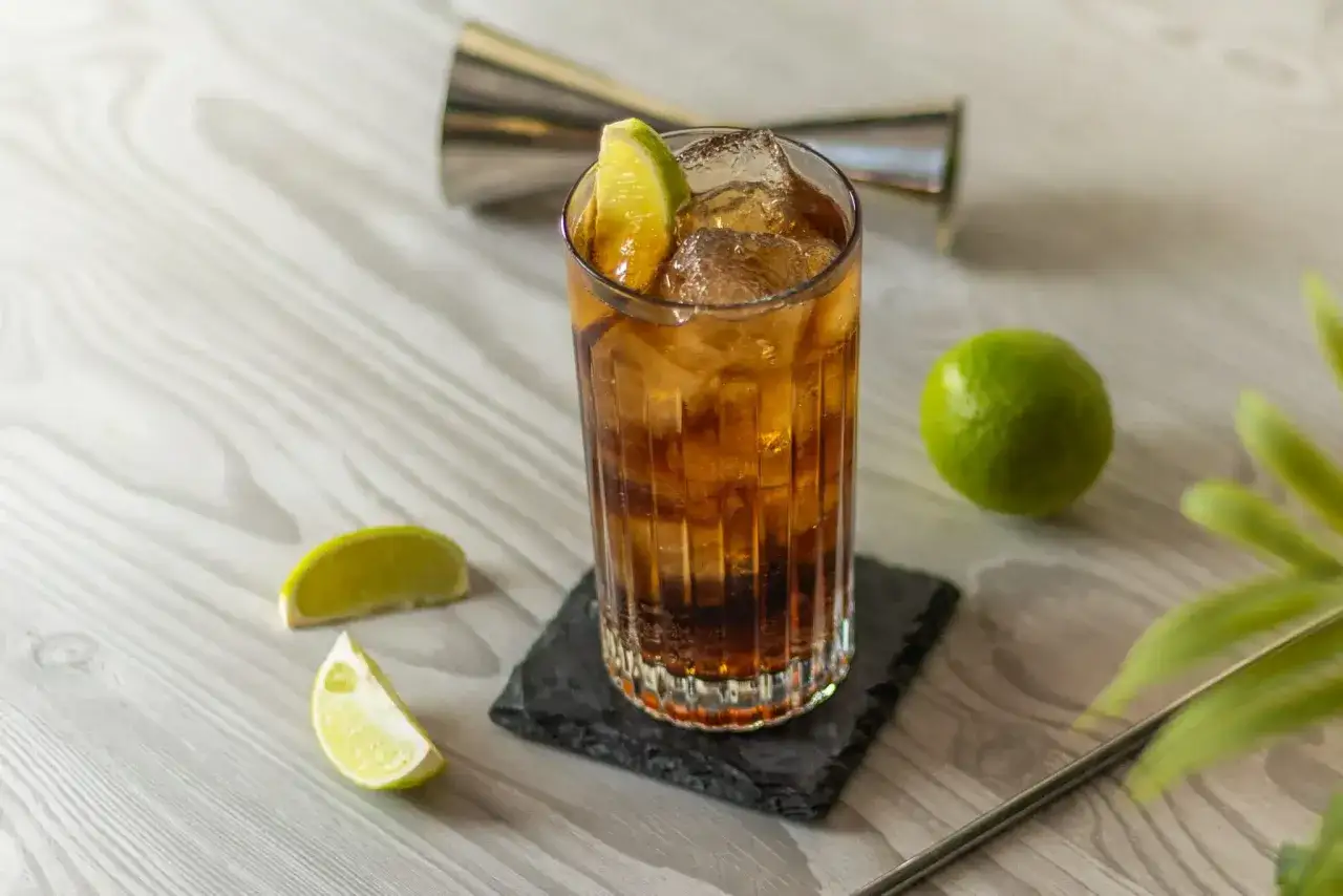 Orzeźwiający drink: whisky z colą, lodem i limonką. Idealny na letnie wieczory.